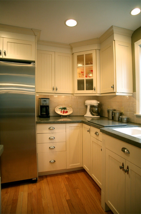 Example of a trendy galley medium tone wood floor eat-in kitchen design in Boston with an integrated sink, shaker cabinets, white cabinets, solid surface countertops, white backsplash, ceramic backsplash, stainless steel appliances and an island