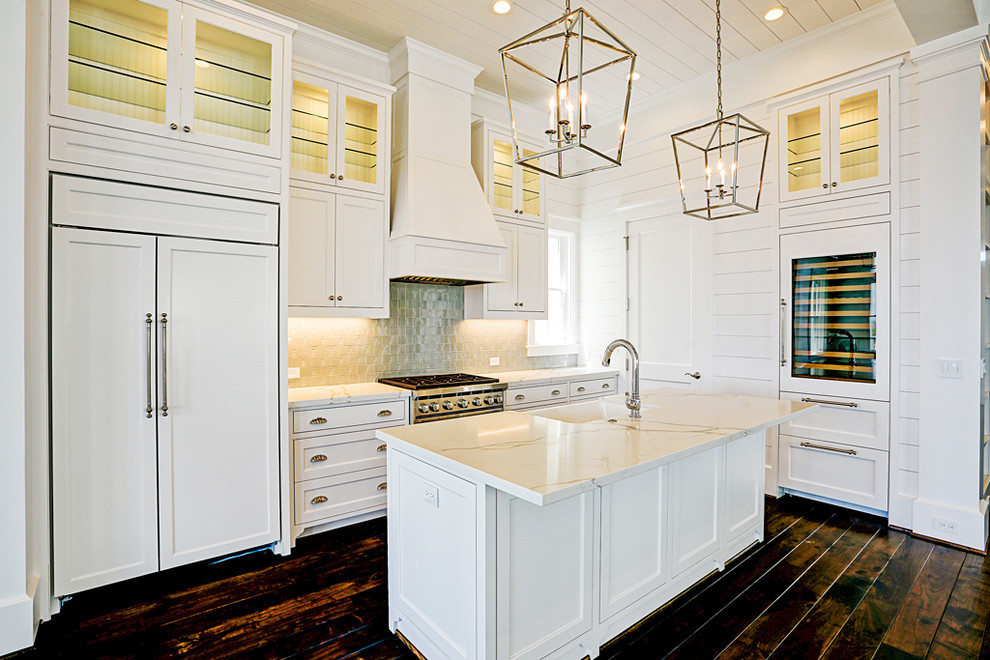 Design ideas for a coastal l-shaped kitchen in Houston with a belfast sink, white cabinets, engineered stone countertops, integrated appliances, dark hardwood flooring, an island and brown floors.