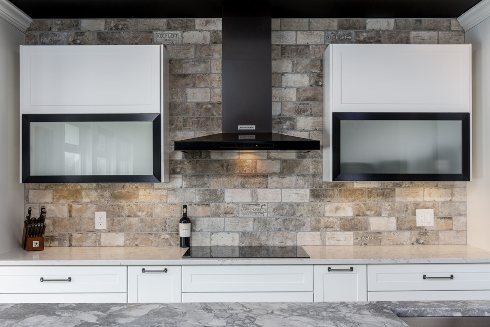 Immagine di una cucina design di medie dimensioni con lavello sottopiano, ante in stile shaker, ante bianche, top in granito, paraspruzzi grigio, paraspruzzi in travertino, elettrodomestici neri, pavimento in laminato, pavimento grigio e top grigio