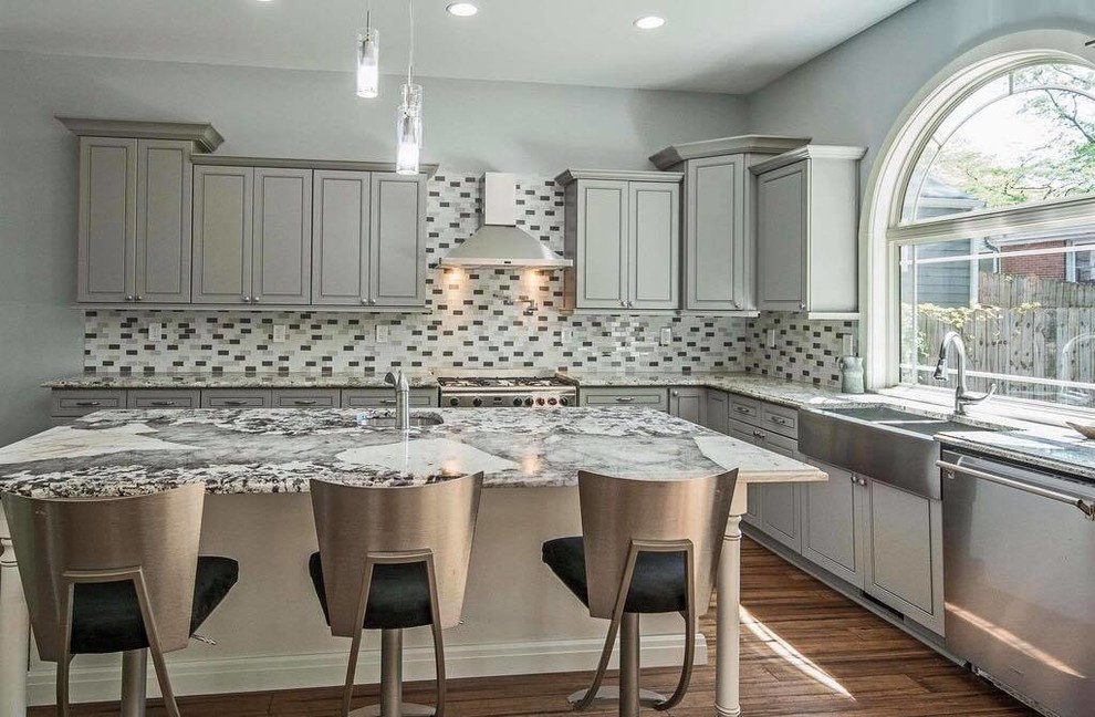 Example of a mid-sized trendy l-shaped dark wood floor and brown floor open concept kitchen design in Atlanta with a farmhouse sink, raised-panel cabinets, gray cabinets, quartzite countertops, multicolored backsplash, matchstick tile backsplash, stainless steel appliances, an island and multicolored countertops