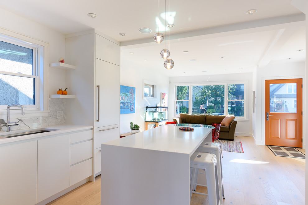 Example of a small trendy l-shaped light wood floor and brown floor eat-in kitchen design in Vancouver with a double-bowl sink, flat-panel cabinets, white cabinets, quartzite countertops, white backsplash, marble backsplash, stainless steel appliances, an island and white countertops