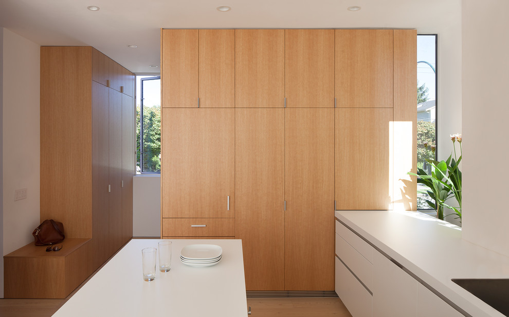 Foto de cocina comedor minimalista de tamaño medio con fregadero bajoencimera, armarios con paneles lisos, puertas de armario de madera oscura, encimera de laminado, salpicadero blanco, salpicadero de azulejos de cerámica, electrodomésticos con paneles, suelo de madera en tonos medios y una isla