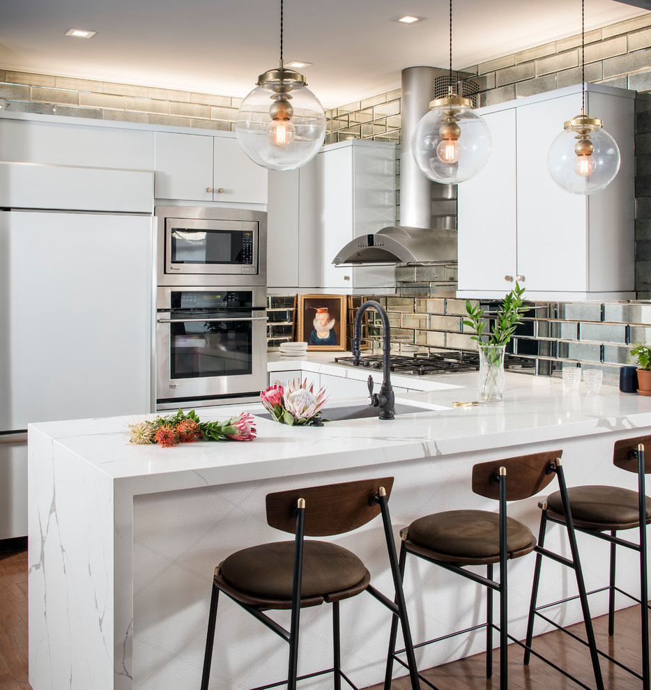 Mid-sized eclectic u-shaped medium tone wood floor and brown floor kitchen photo in San Francisco with flat-panel cabinets, white cabinets, quartz countertops, metallic backsplash, mirror backsplash, a peninsula, an undermount sink, white appliances and white countertops