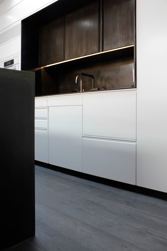 Ejemplo de cocina lineal nórdica con armarios con paneles lisos, puertas de armario blancas, salpicadero marrón, suelo de madera oscura y suelo gris