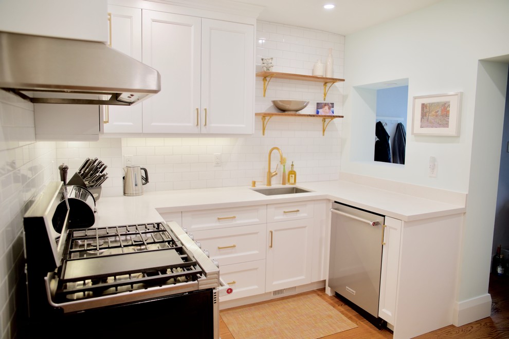 Inredning av ett modernt avskilt, litet vit vitt u-kök, med en undermonterad diskho, skåp i shakerstil, vita skåp, bänkskiva i kvarts, vitt stänkskydd, stänkskydd i keramik, rostfria vitvaror, mellanmörkt trägolv och brunt golv