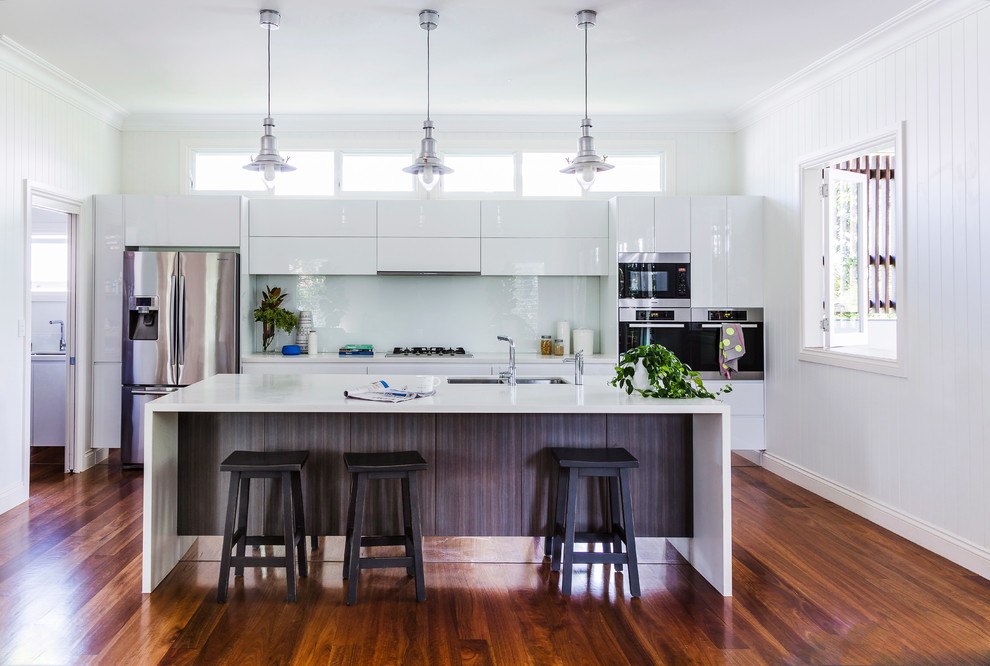Inspiration for a contemporary medium tone wood floor kitchen remodel in Sydney with an undermount sink, flat-panel cabinets, white cabinets, white backsplash, stainless steel appliances and an island