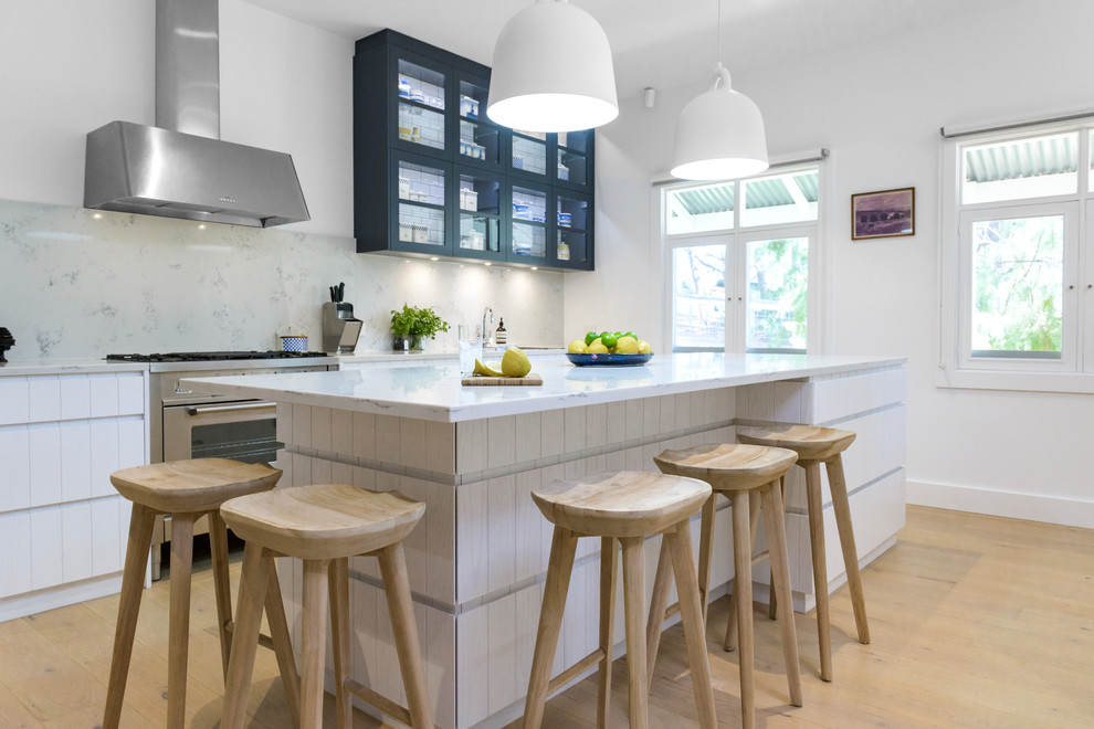 Trendy galley light wood floor and beige floor eat-in kitchen photo in Adelaide with flat-panel cabinets, white cabinets, gray backsplash, glass sheet backsplash, stainless steel appliances, an island and gray countertops