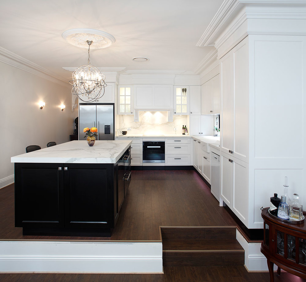 Example of a mid-sized classic l-shaped dark wood floor eat-in kitchen design in Sydney with a farmhouse sink, recessed-panel cabinets, white cabinets, marble countertops, multicolored backsplash, stone slab backsplash, stainless steel appliances and an island