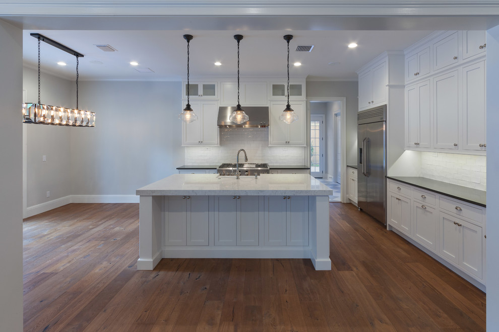 Inspiration for a huge timeless l-shaped medium tone wood floor eat-in kitchen remodel in Orlando with a farmhouse sink, beaded inset cabinets, stainless steel cabinets, quartzite countertops, white backsplash, subway tile backsplash, stainless steel appliances and an island