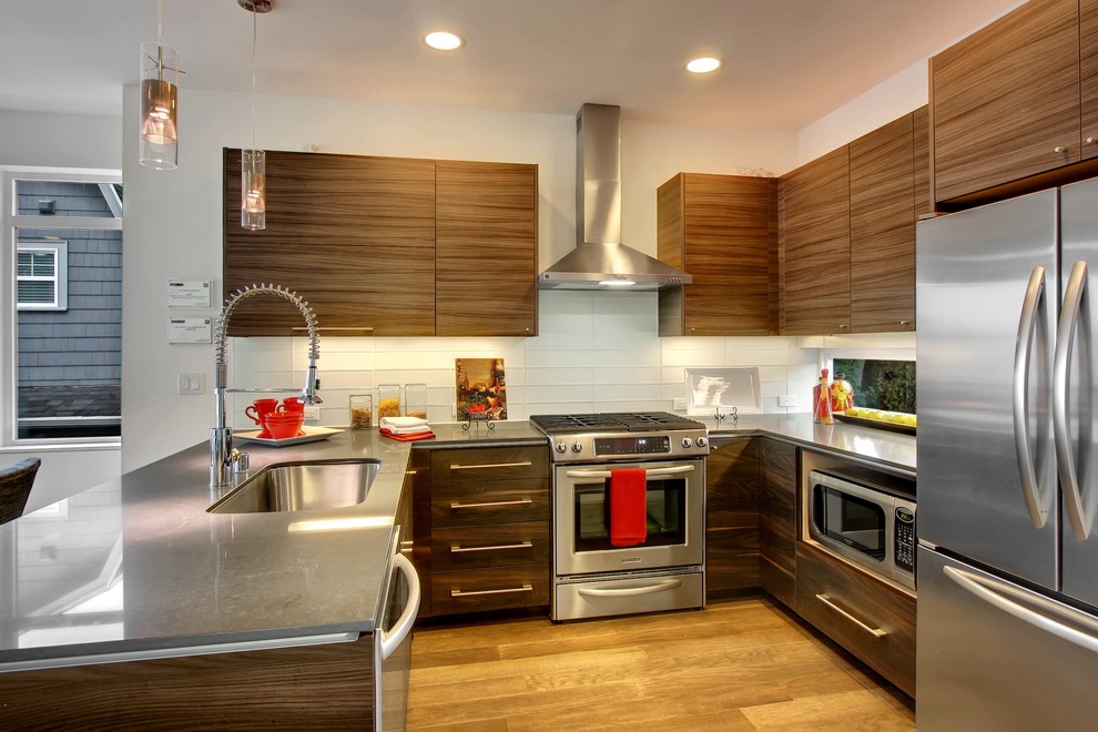 Moderne Küche in U-Form mit Waschbecken, flächenbündigen Schrankfronten, hellbraunen Holzschränken, Küchenrückwand in Weiß und Küchengeräten aus Edelstahl in Seattle
