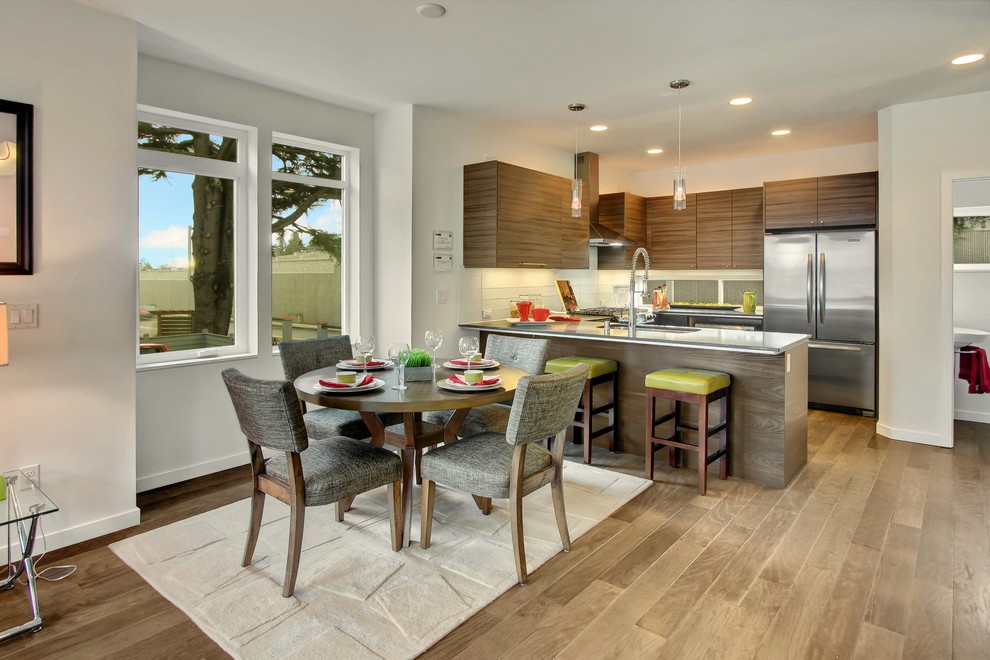 Moderne Wohnküche in U-Form mit flächenbündigen Schrankfronten, hellbraunen Holzschränken, Küchenrückwand in Weiß und Küchengeräten aus Edelstahl in Seattle