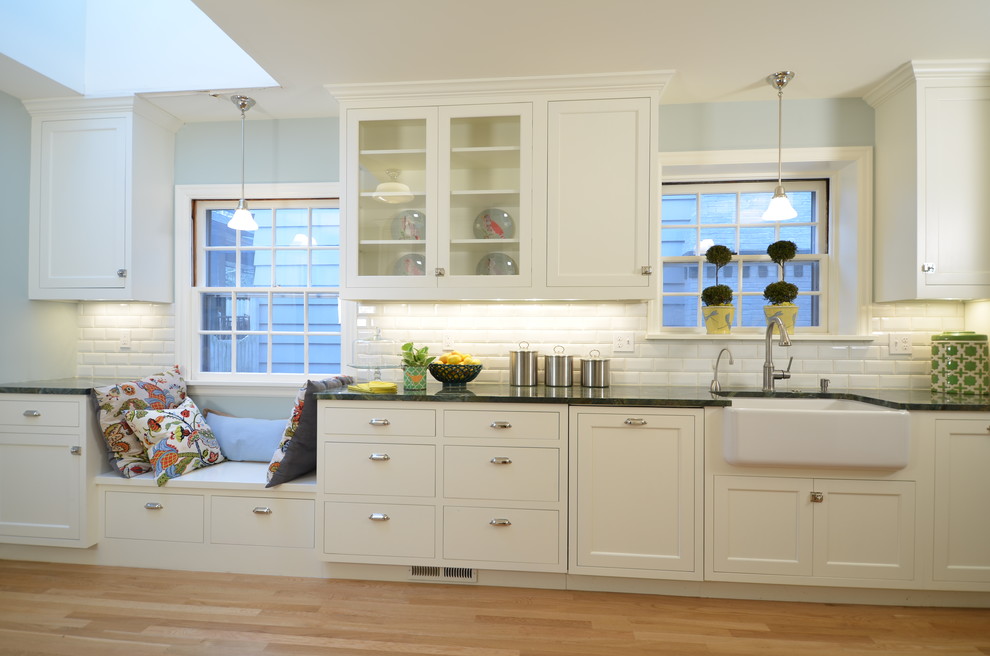 Amerikansk inredning av ett mellanstort kök, med en rustik diskho, skåp i shakerstil, vita skåp, granitbänkskiva, vitt stänkskydd, stänkskydd i keramik, rostfria vitvaror och ljust trägolv