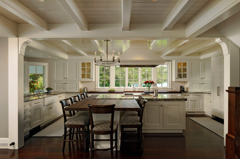 Inspiration for a large timeless u-shaped dark wood floor eat-in kitchen remodel in Baltimore with white cabinets, granite countertops, white backsplash, subway tile backsplash, an island, recessed-panel cabinets, paneled appliances and a farmhouse sink
