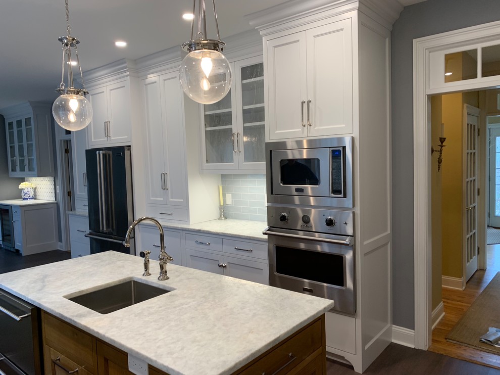 Inredning av ett klassiskt mycket stort grå grått kök, med en enkel diskho, luckor med infälld panel, vita skåp, bänkskiva i kvartsit, blått stänkskydd, stänkskydd i keramik, rostfria vitvaror, korkgolv, en köksö och brunt golv