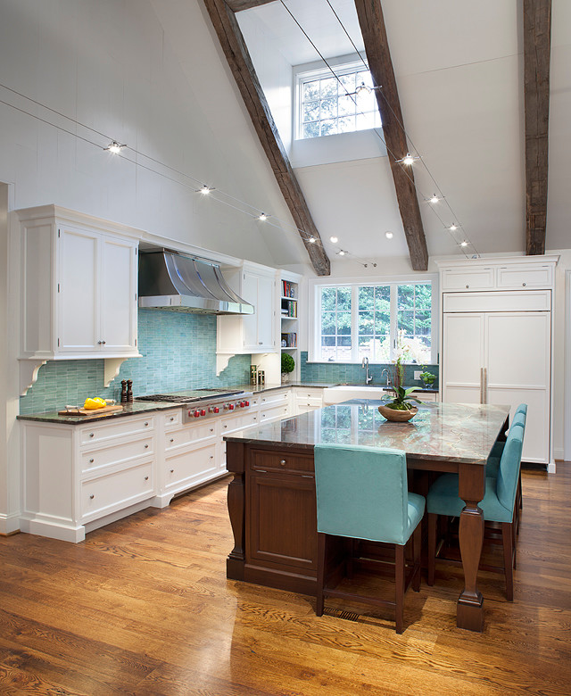 Inspiration for a large transitional l-shaped medium tone wood floor and brown floor eat-in kitchen remodel in Charlotte with a farmhouse sink, recessed-panel cabinets, white cabinets, quartzite countertops, blue backsplash, glass tile backsplash, paneled appliances and an island