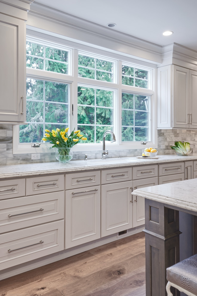 Exempel på ett avskilt, mellanstort modernt grå grått u-kök, med en undermonterad diskho, skåp i shakerstil, beige skåp, granitbänkskiva, flerfärgad stänkskydd, stänkskydd i mosaik, rostfria vitvaror, mellanmörkt trägolv och en köksö