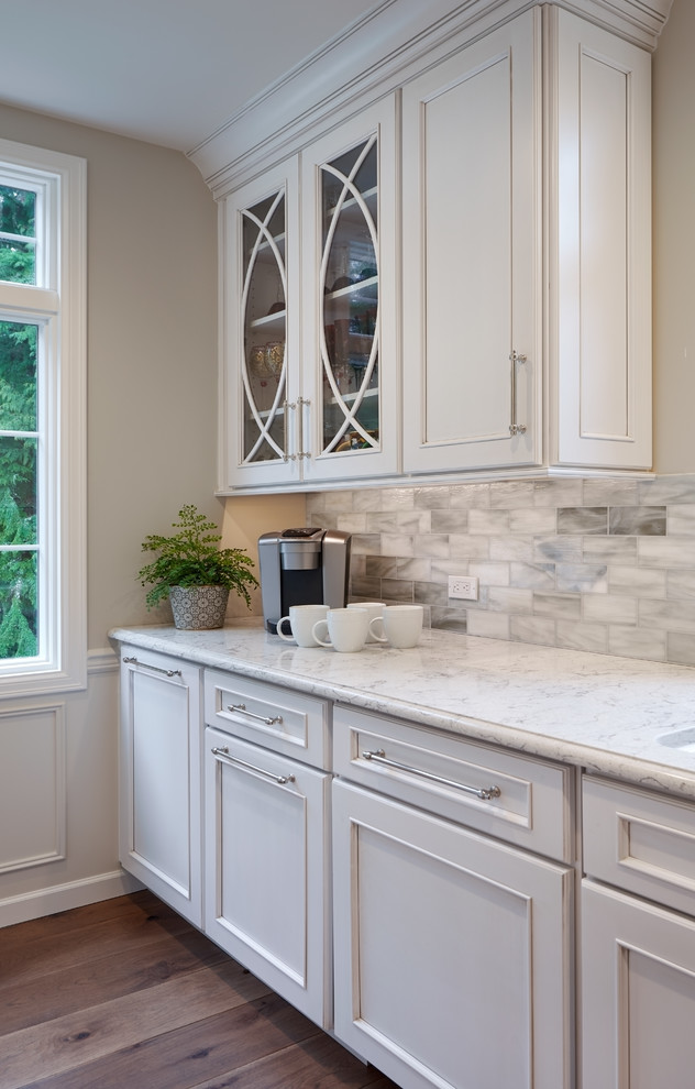 Inspiration for a mid-sized contemporary u-shaped medium tone wood floor enclosed kitchen remodel in Seattle with an undermount sink, shaker cabinets, beige cabinets, granite countertops, multicolored backsplash, mosaic tile backsplash, stainless steel appliances, an island and gray countertops