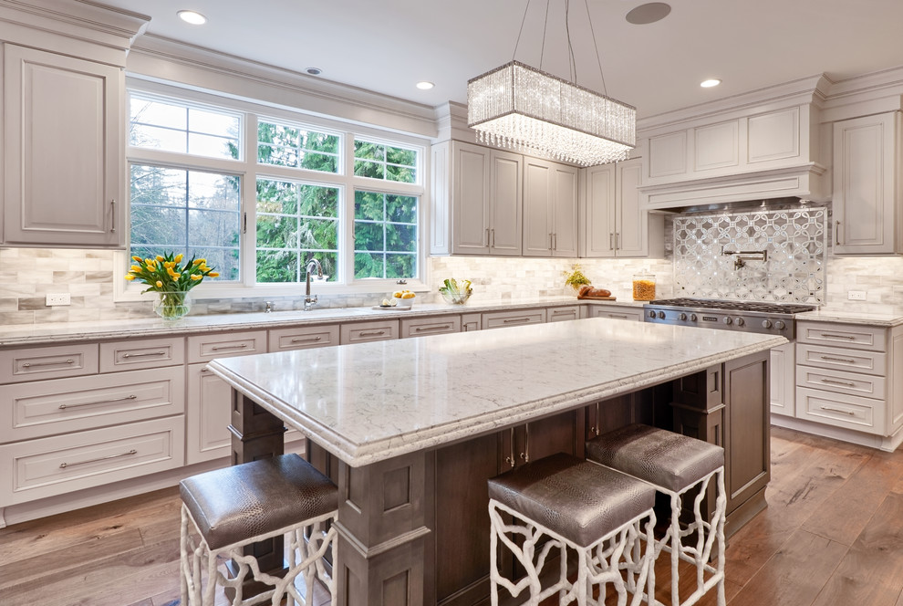 Inspiration for a mid-sized transitional l-shaped medium tone wood floor and brown floor kitchen remodel in Seattle with an undermount sink, beige cabinets, granite countertops, multicolored backsplash, mosaic tile backsplash, stainless steel appliances, an island, gray countertops and beaded inset cabinets