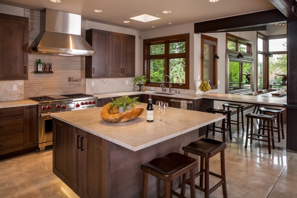 Foto på ett stort funkis kök, med granitbänkskiva, beige stänkskydd, rostfria vitvaror, betonggolv, en köksö, en undermonterad diskho, skåp i shakerstil och skåp i mörkt trä