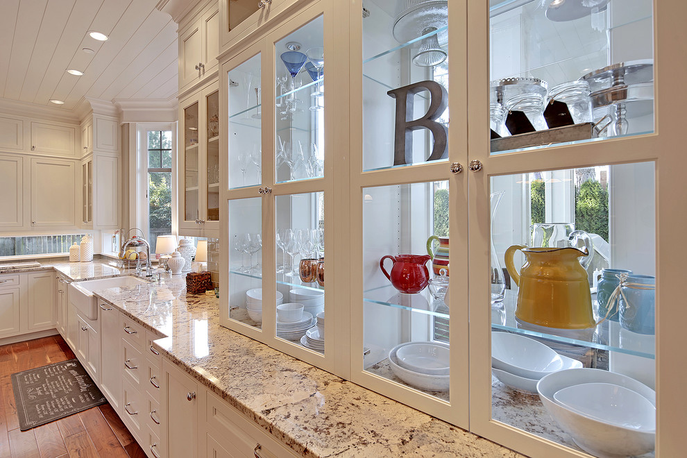 Klassisk inredning av ett stort kök och matrum, med en rustik diskho, skåp i shakerstil, vita skåp, granitbänkskiva, beige stänkskydd, stänkskydd i tunnelbanekakel, rostfria vitvaror, mellanmörkt trägolv och en köksö