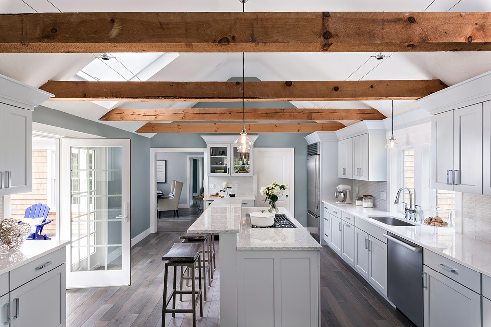 Beach style galley dark wood floor and brown floor kitchen photo in Boston with an undermount sink, shaker cabinets, gray cabinets, white backsplash, mosaic tile backsplash, stainless steel appliances and an island