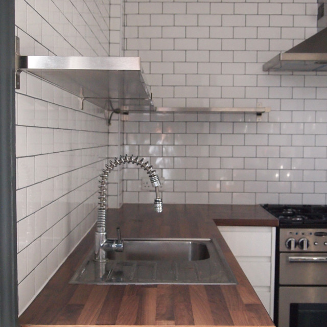 Idéer för ett mellanstort modernt kök, med en integrerad diskho, grå skåp, laminatbänkskiva, vitt stänkskydd, stänkskydd i tunnelbanekakel, rostfria vitvaror och travertin golv