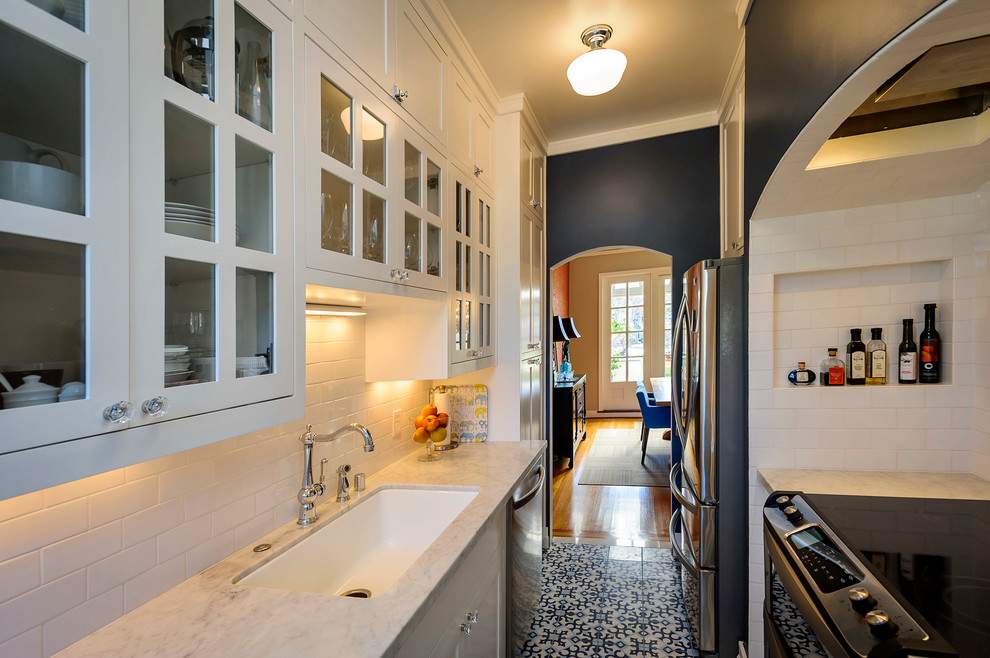 サンフランシスコにある地中海スタイルのおしゃれなキッチン (ガラス扉のキャビネット、シングルシンク、シルバーの調理設備、サブウェイタイルのキッチンパネル) の写真
