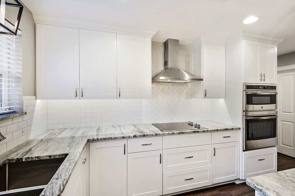 Idées déco pour une cuisine américaine classique en L de taille moyenne avec un évier encastré, un placard à porte shaker, des portes de placard blanches, un plan de travail en granite, une crédence blanche, une crédence en carrelage métro, un électroménager en acier inoxydable, un sol en vinyl, îlot et un sol marron.