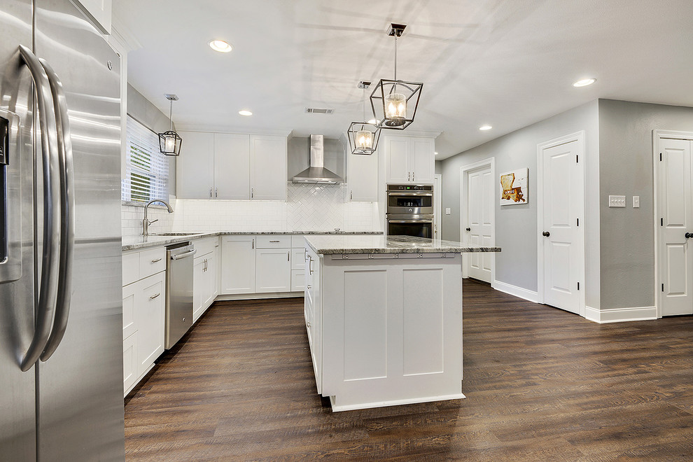Inspiration for a medium sized traditional l-shaped kitchen/diner in New Orleans with a submerged sink, shaker cabinets, white cabinets, granite worktops, white splashback, metro tiled splashback, stainless steel appliances, vinyl flooring, an island and brown floors.