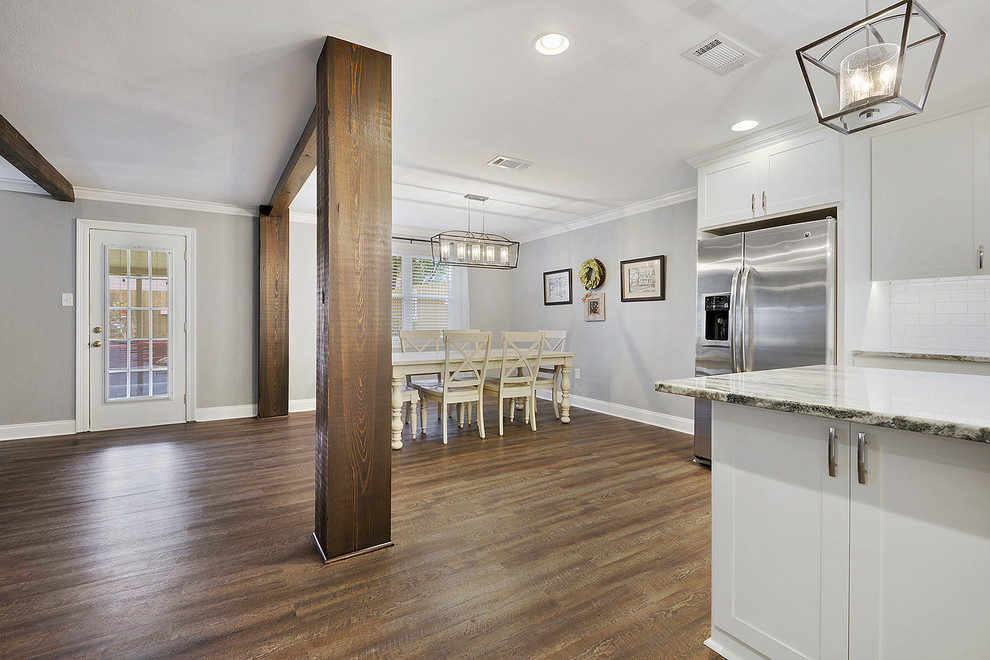 Exempel på ett mellanstort klassiskt kök, med en undermonterad diskho, skåp i shakerstil, vita skåp, granitbänkskiva, vitt stänkskydd, stänkskydd i tunnelbanekakel, rostfria vitvaror, vinylgolv, en köksö och brunt golv