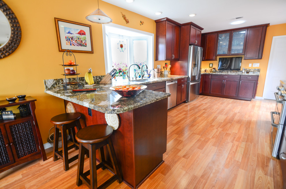 Design ideas for a large contemporary galley kitchen/diner in Tampa with a single-bowl sink, recessed-panel cabinets, red cabinets, granite worktops, yellow splashback, glass tiled splashback, stainless steel appliances and medium hardwood flooring.