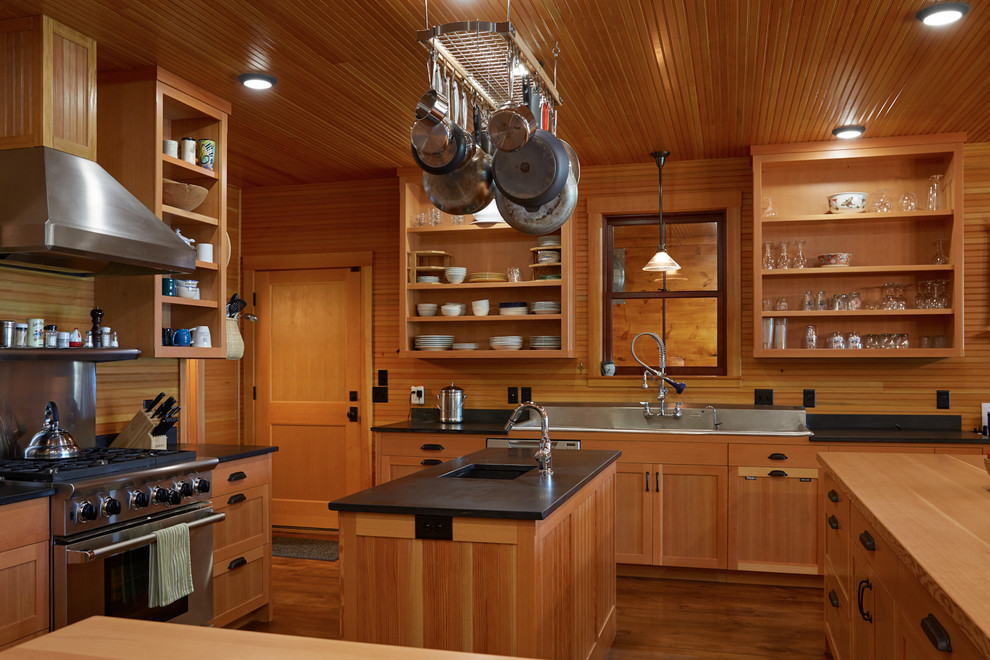 Inspiration for a mid-sized rustic u-shaped medium tone wood floor eat-in kitchen remodel in Portland Maine with stainless steel appliances, a drop-in sink, raised-panel cabinets, medium tone wood cabinets, solid surface countertops, black backsplash, wood backsplash and an island
