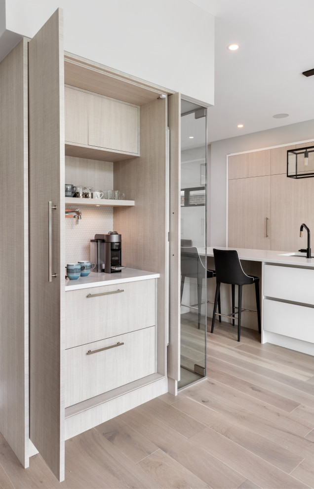 Diseño de cocina contemporánea con armarios con paneles lisos, puertas de armario de madera clara, suelo de madera clara, suelo beige y encimeras blancas