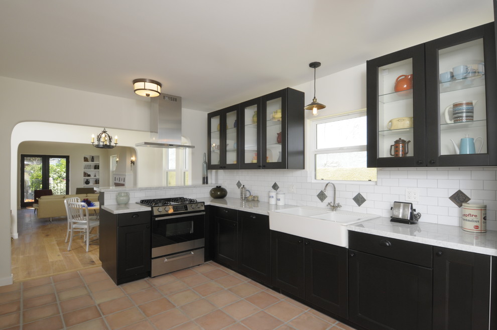 Foto på ett mellanstort medelhavsstil kök, med en halv köksö, skåp i shakerstil, bruna skåp, marmorbänkskiva, vitt stänkskydd, stänkskydd i tunnelbanekakel, integrerade vitvaror, en rustik diskho och klinkergolv i terrakotta