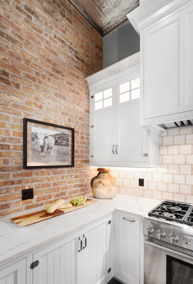 Example of a mid-sized cottage chic l-shaped ceramic tile and gray floor kitchen pantry design in Detroit with a farmhouse sink, shaker cabinets, white cabinets, quartz countertops, beige backsplash, mosaic tile backsplash, stainless steel appliances and an island