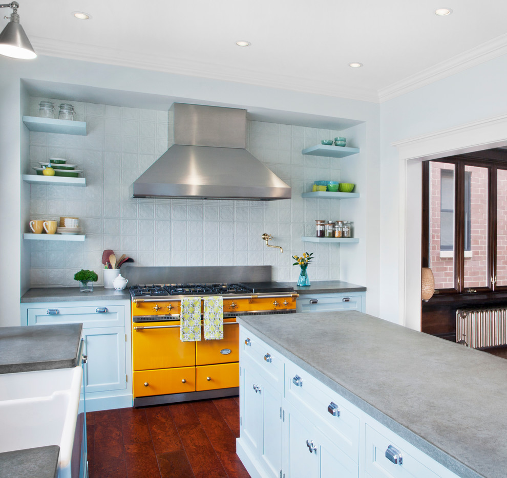 Example of a transitional u-shaped eat-in kitchen design in Chicago with a farmhouse sink, shaker cabinets, blue cabinets, concrete countertops and colored appliances