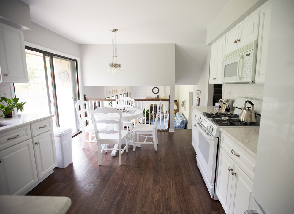 Eat-in kitchen - small farmhouse vinyl floor and brown floor eat-in kitchen idea in Chicago with a double-bowl sink, raised-panel cabinets, white cabinets, quartz countertops, white backsplash, ceramic backsplash, white appliances and no island