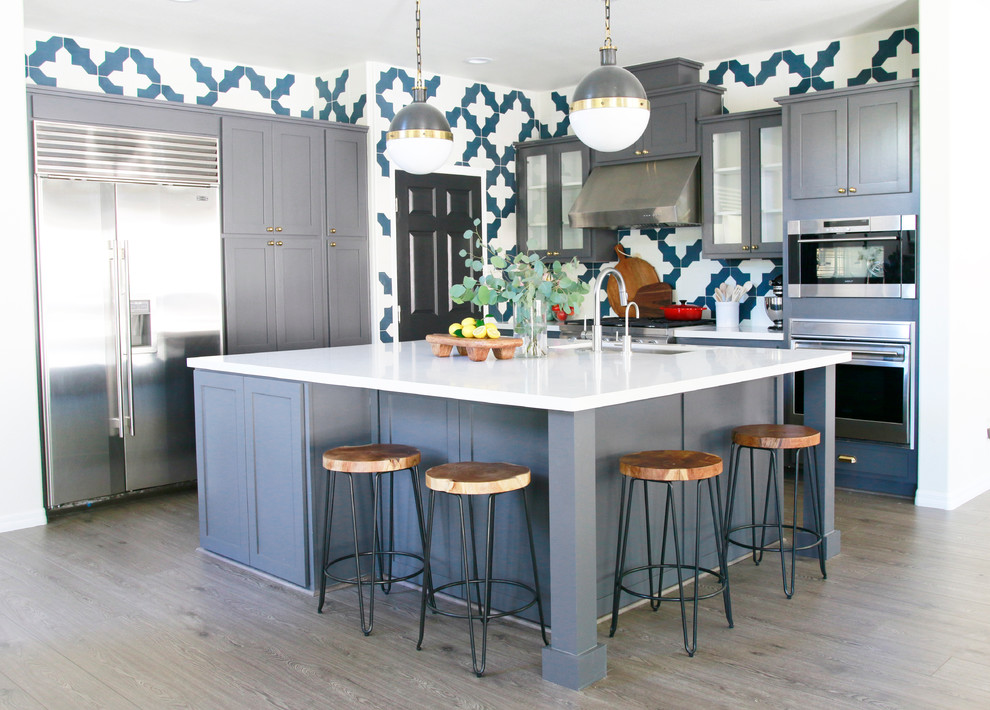 Inspiration for a transitional light wood floor kitchen remodel in Las Vegas with shaker cabinets, gray cabinets, multicolored backsplash, ceramic backsplash, stainless steel appliances and an island