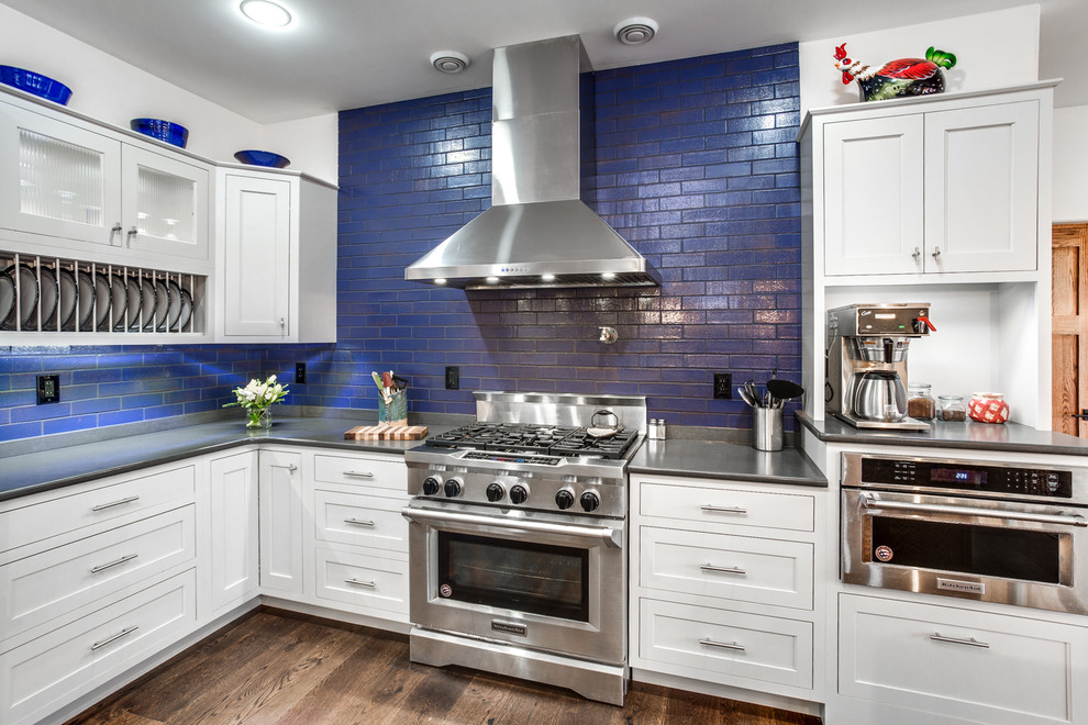 Inredning av ett eklektiskt mellanstort kök, med en rustik diskho, luckor med profilerade fronter, vita skåp, bänkskiva i kvarts, blått stänkskydd, stänkskydd i tegel, rostfria vitvaror, mörkt trägolv och en köksö