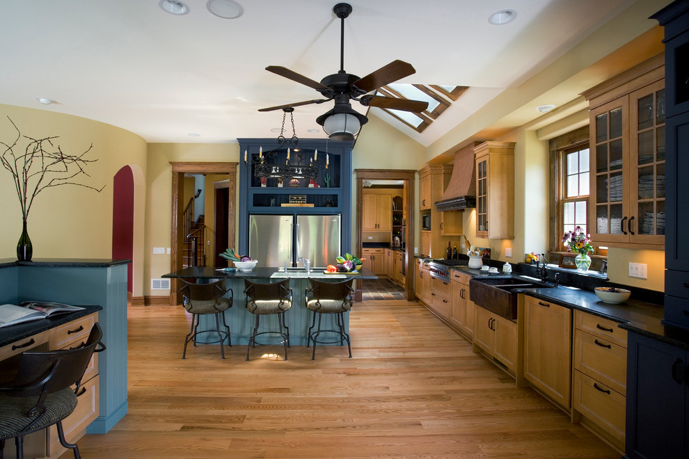 Exempel på ett mellanstort klassiskt kök, med en rustik diskho, luckor med infälld panel, skåp i ljust trä, granitbänkskiva, rostfria vitvaror, ljust trägolv och en köksö