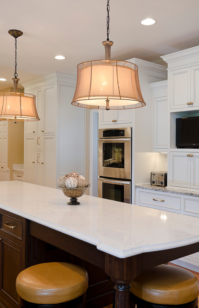Exempel på ett mellanstort klassiskt kök, med luckor med infälld panel, vita skåp, bänkskiva i kvarts, rostfria vitvaror, en köksö, en undermonterad diskho, mellanmörkt trägolv, vitt stänkskydd och stänkskydd i stenkakel