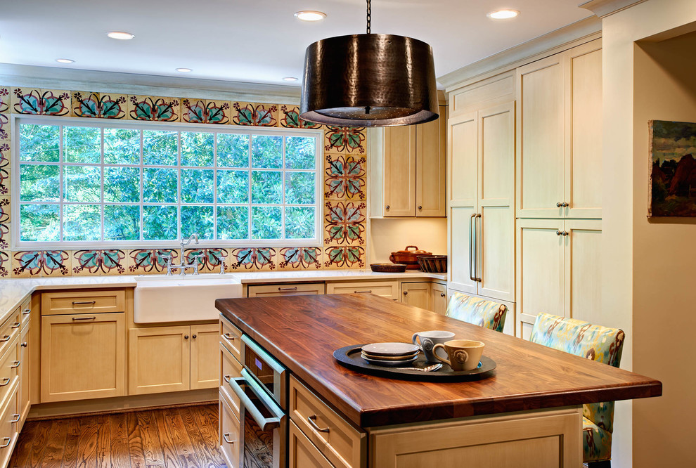 Elegant kitchen photo in Charlotte with a farmhouse sink, wood countertops, shaker cabinets, multicolored backsplash and paneled appliances