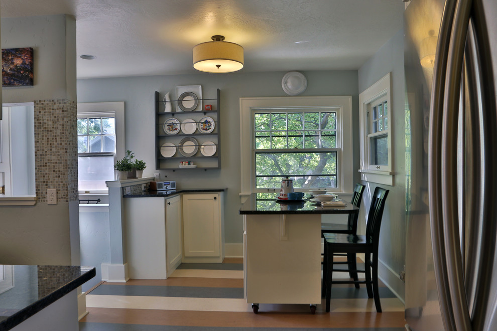 Eat-in kitchen - small eclectic l-shaped linoleum floor eat-in kitchen idea in Boise with an undermount sink, recessed-panel cabinets, white cabinets, granite countertops, multicolored backsplash, mosaic tile backsplash, stainless steel appliances and an island