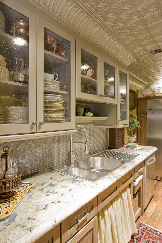 Inspiration for a timeless kitchen remodel in Phoenix with a drop-in sink, glass-front cabinets, gray cabinets, gray backsplash, mosaic tile backsplash, stainless steel appliances and granite countertops