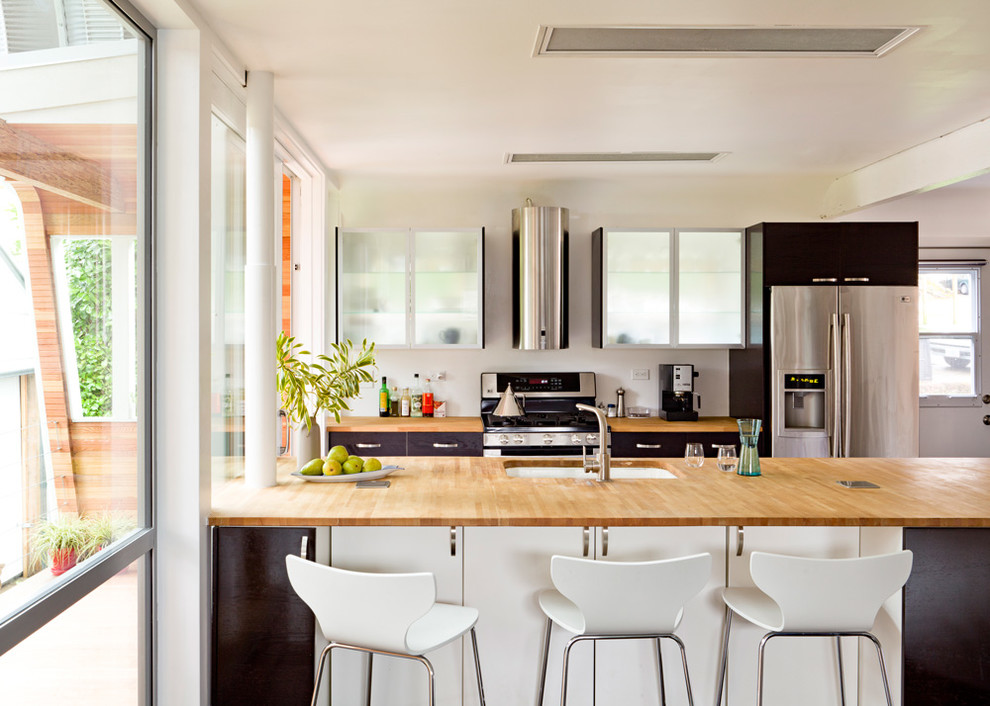 Foto de cocina bohemia con electrodomésticos de acero inoxidable, encimera de madera, armarios con paneles lisos, puertas de armario negras y barras de cocina