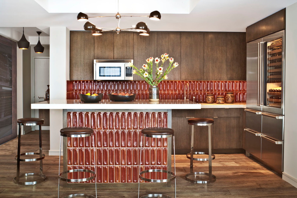 ロサンゼルスにあるエクレクティックスタイルのおしゃれなL型キッチン (フラットパネル扉のキャビネット、濃色木目調キャビネット、赤いキッチンパネル、シルバーの調理設備) の写真