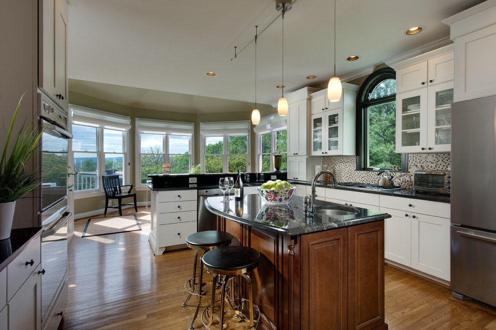 Exempel på ett stort klassiskt kök, med rostfria vitvaror, luckor med infälld panel, vita skåp, flerfärgad stänkskydd, mellanmörkt trägolv, en köksö och brunt golv