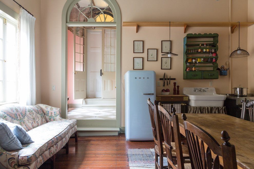 Einzeilige Shabby-Chic Wohnküche ohne Insel mit Landhausspüle, grünen Schränken, bunten Elektrogeräten und dunklem Holzboden in New Orleans