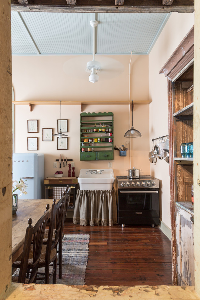 Shabby chic-inspirerad inredning av ett linjärt kök och matrum, med en rustik diskho, färgglada vitvaror och mörkt trägolv