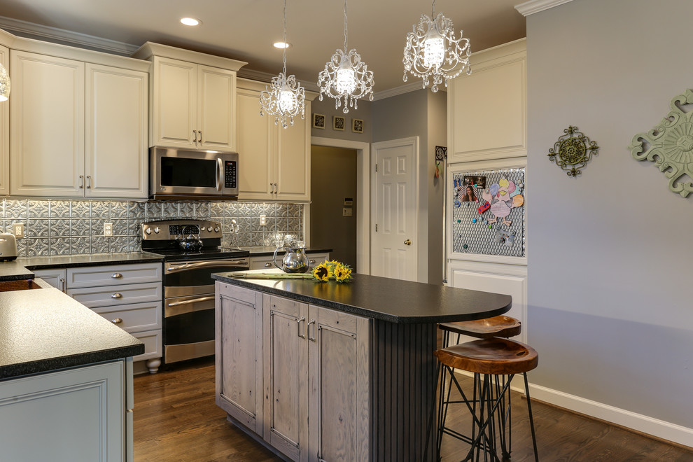 Eat-in kitchen - mid-sized eclectic l-shaped eat-in kitchen idea in Raleigh with a farmhouse sink, raised-panel cabinets, gray cabinets, granite countertops, gray backsplash, metal backsplash, stainless steel appliances and an island